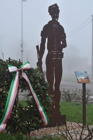 Scultura del Partigiano con corona di alloro, nel contesto di una giornata nebbiosa.