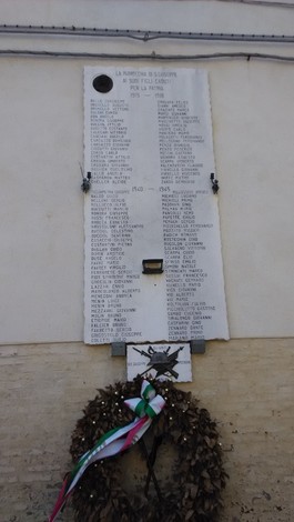 Lapide commemorativa dedicata ai caduti di San Giuseppe, con elenco di nomi e decorazioni floreali.