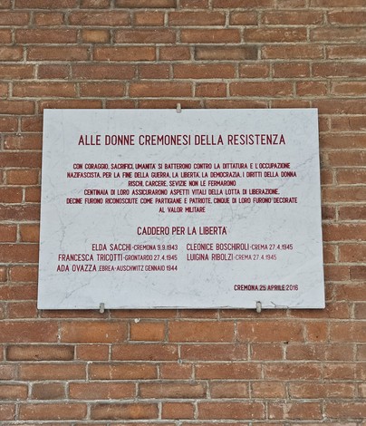 Lapide dedicata alle donne cremonesi della Resistenza, commemorativa e suggestiva, su muro di mattoni.