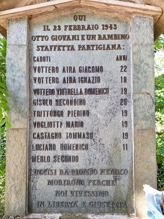 Monumento che commemorano i giovani partigiani caduti, circondato da una vegetazione lussureggiante.