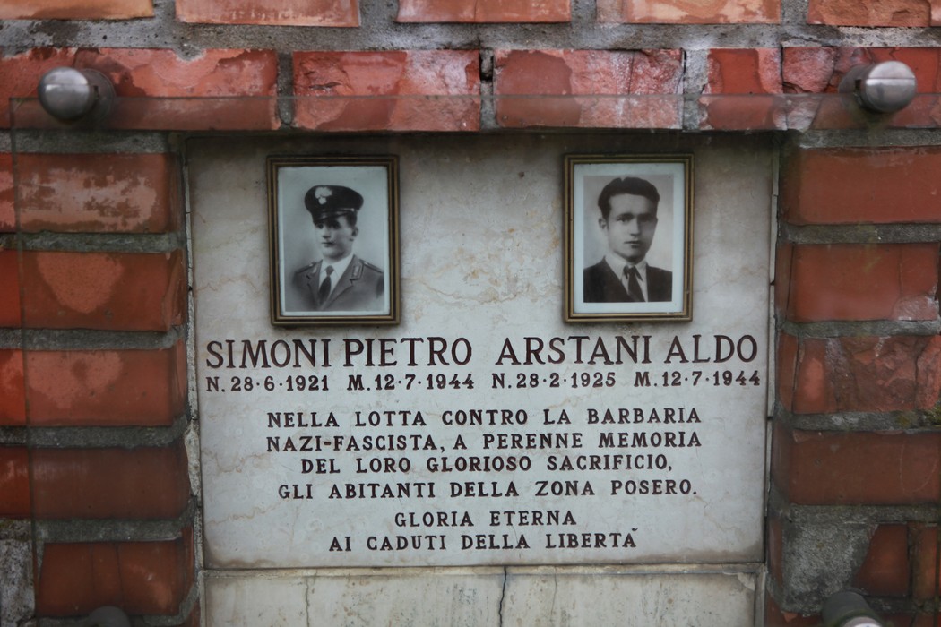 Cippo commemorativo dedicato a Simoni e Arstani, con foto e iscrizione in memoria degli abitanti della zona.