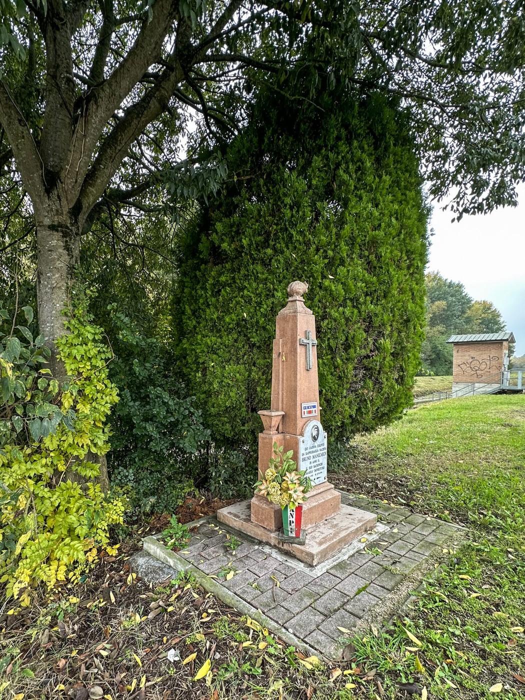 Cippo a Manicardi, monumento in pietra circondato da alberi e vegetazione, simbolo di memoria e devozione.