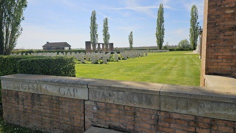 Cimitero di guerra di Argenta, con filari di tombe bianche e un paesaggio verde curato.