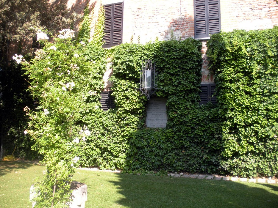 Lapide commemorativa per le vittime di torture al Castello di Cigognola, immersa nel verde.