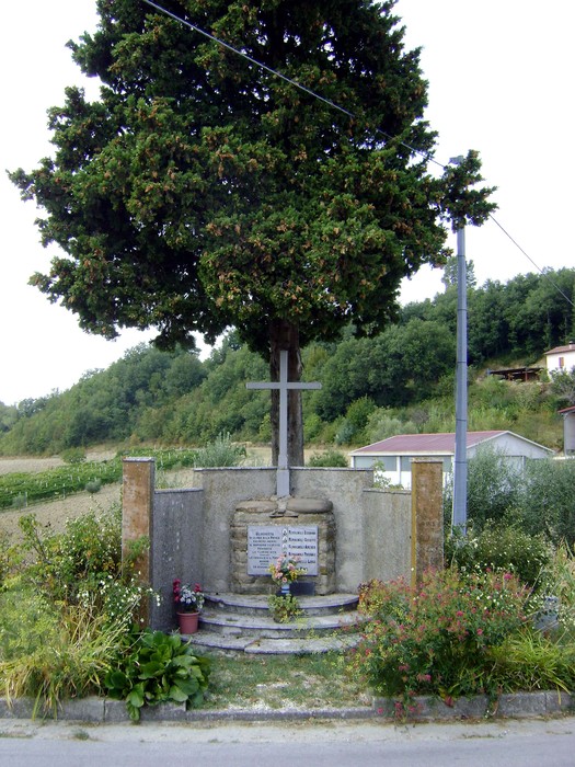 Monumento commemorativo ai Caduti dell'eccidio di Montalvello, immerso nel verde e adornato da fiori.