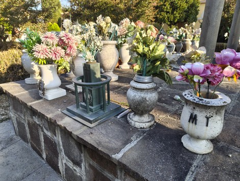 Sacrario ai caduti con vasi di fiori e ritratti commemorativi su una base di pietra.
