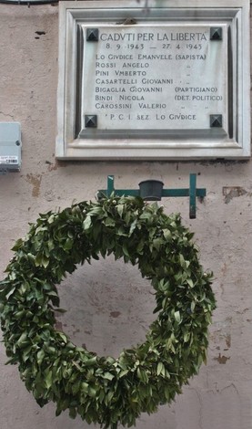 Lapide commemorativa in onore dei caduti per la libertà, con una corona di alloro.