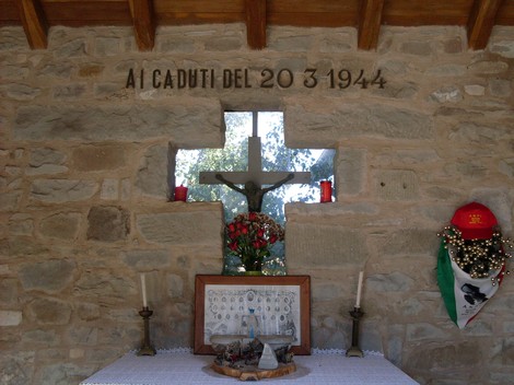 Aia di Cervarolo: cappella commemorativa con croce e omaggio floreale ai caduti del 1944.