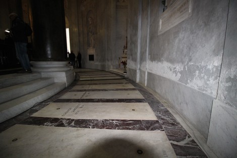Lapide commemorativa di Gastaldi all'interno di una chiesa, con un pavimento di marmo e leggeri giochi di luce.