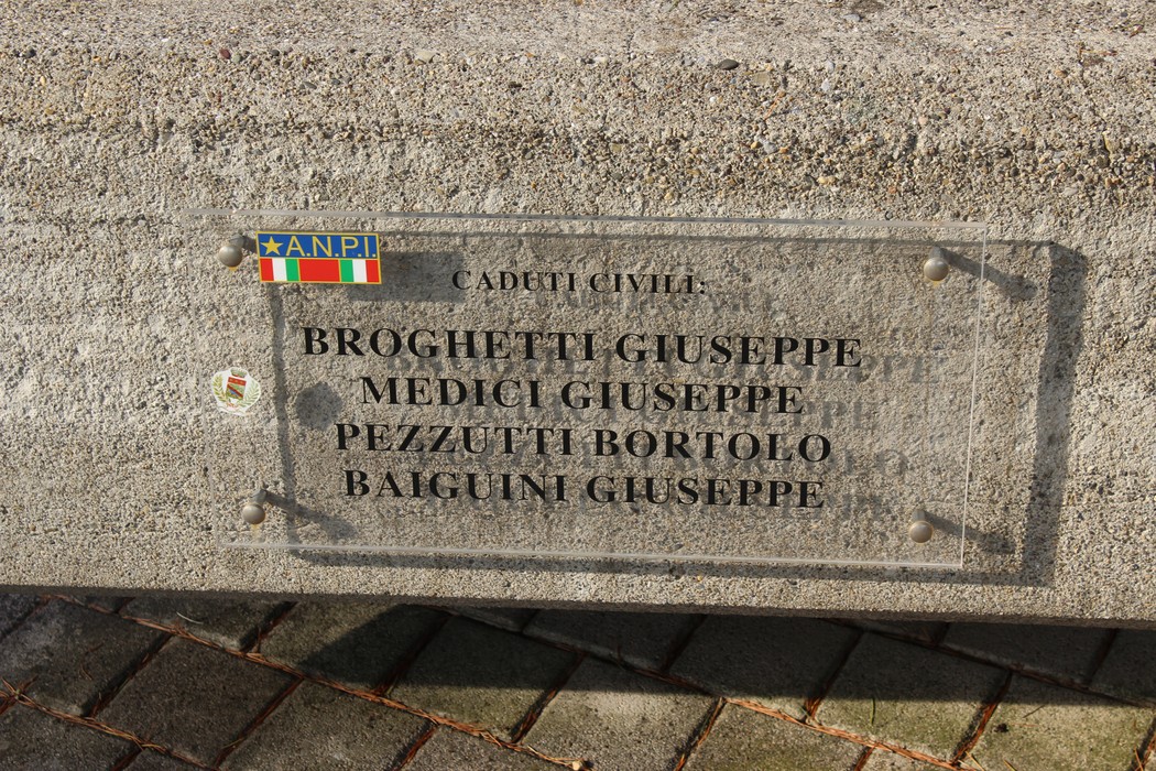 Monumento ai caduti partigiani con targhe commemorative di diversi nomi su una base in pietra.