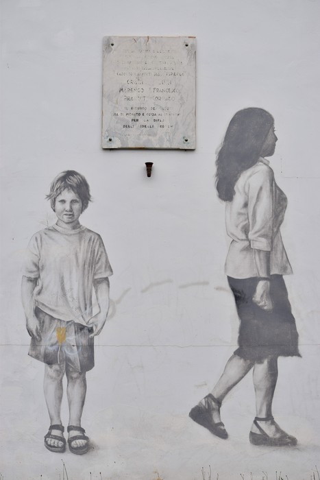 Lapide dedicata ai Sappisti della Superga, affiancata da murales che raffigurano due figure umane.