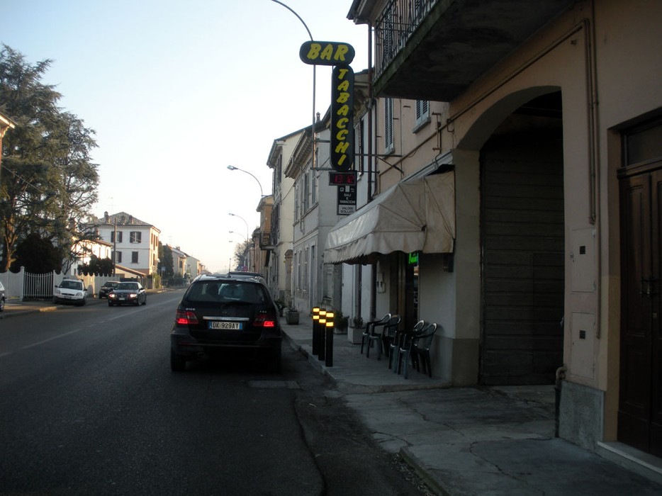 Immagine che mostra il Bar Stadiaccin nella località di Perduca, con strada e edifici circostanti.