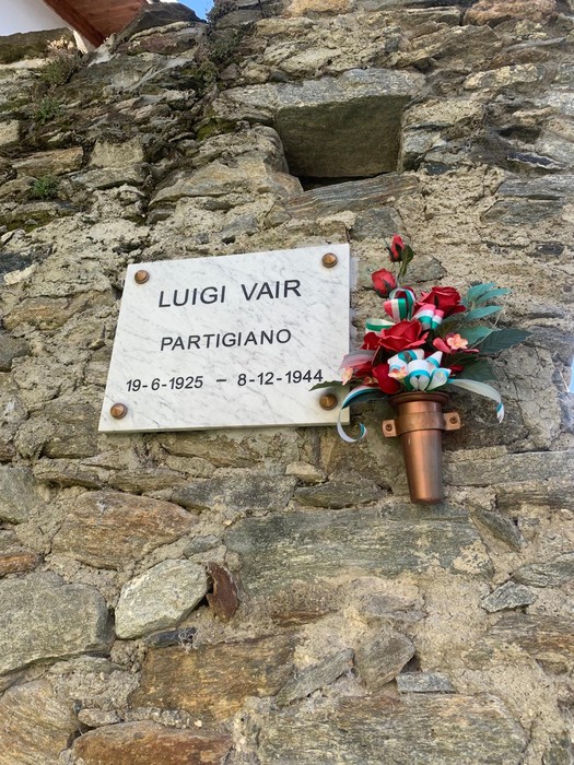 Lapide commemorativa di Luigi Vair, partigiano, con decorazione floreale.