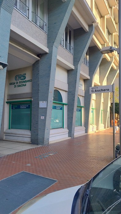 Portico di un edificio con targa stradale bianca "C. Aschero" affissa a una colonna.