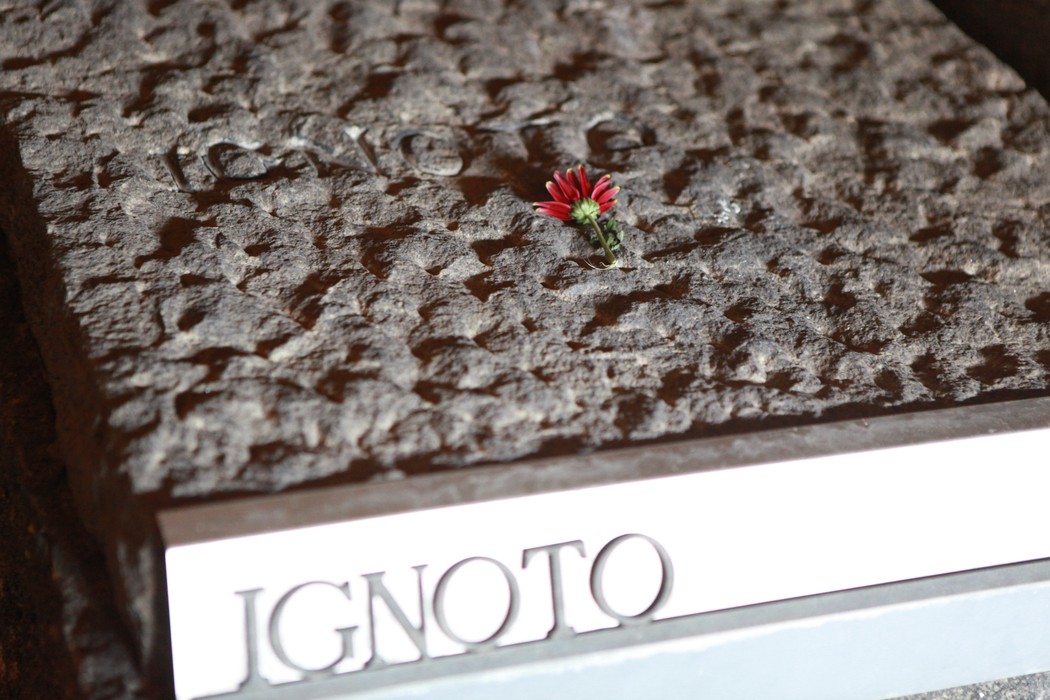 Targa del Mausoleo delle Fosse Ardeatine, con un fiore rosso posato sopra la scritta Ignoto.