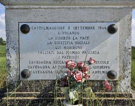 Cippo commemorativo ai Martiri di Bondanello, situato in un paesaggio rurale, con fiori in omaggio ai caduti.