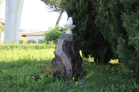 Cippo commemorativo dedicato ai fratelli Mazzola, incastonato nel verde di un giardino.