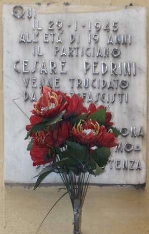 Lapide commemorativa dedicata al partigiano Cesare Pedrini, con fiori rossi in omaggio.