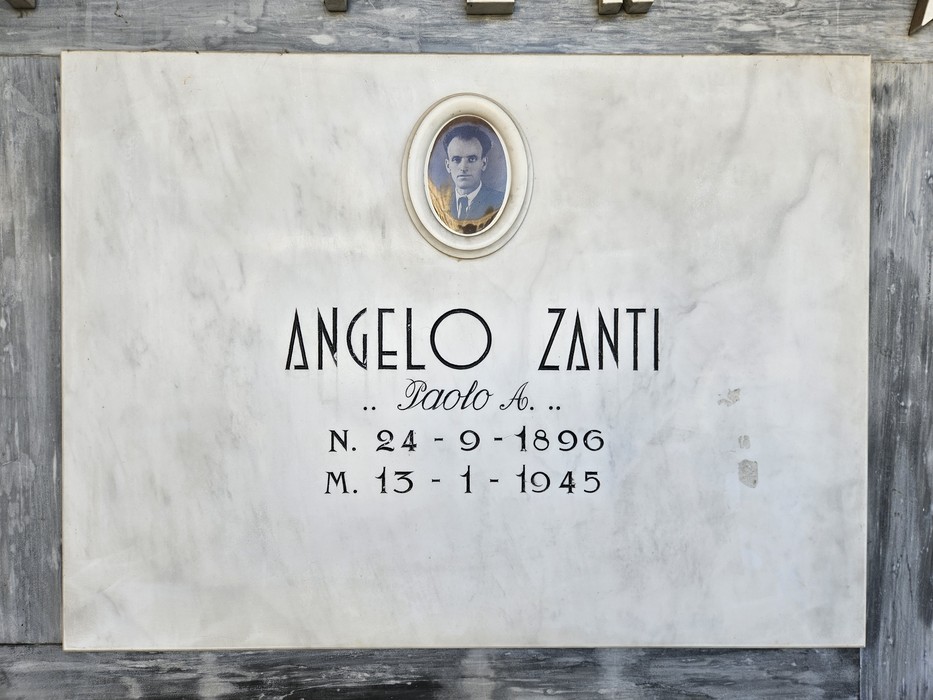 Lapide in marmo con ritratto ovale fotografico e iscrizione dedicata a un caduto.
