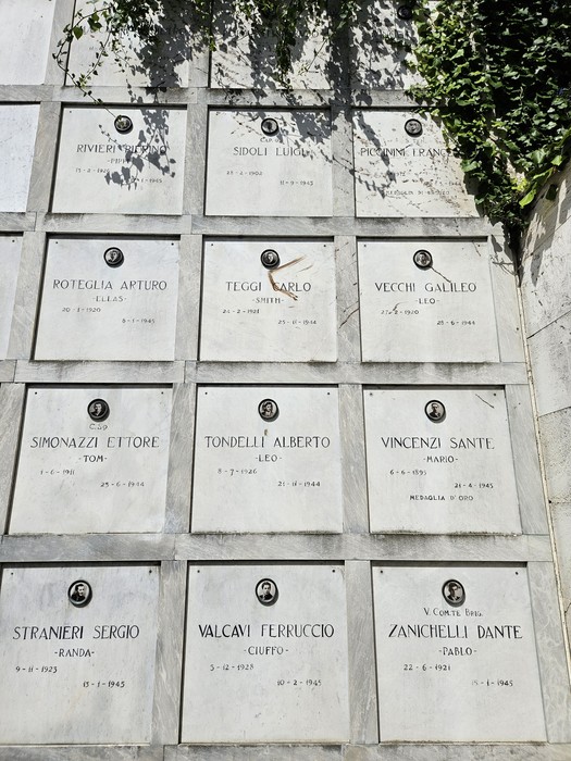 Monumento ai Caduti Partigiani con lapidi commemorative e dettagli vegetali sullo sfondo.