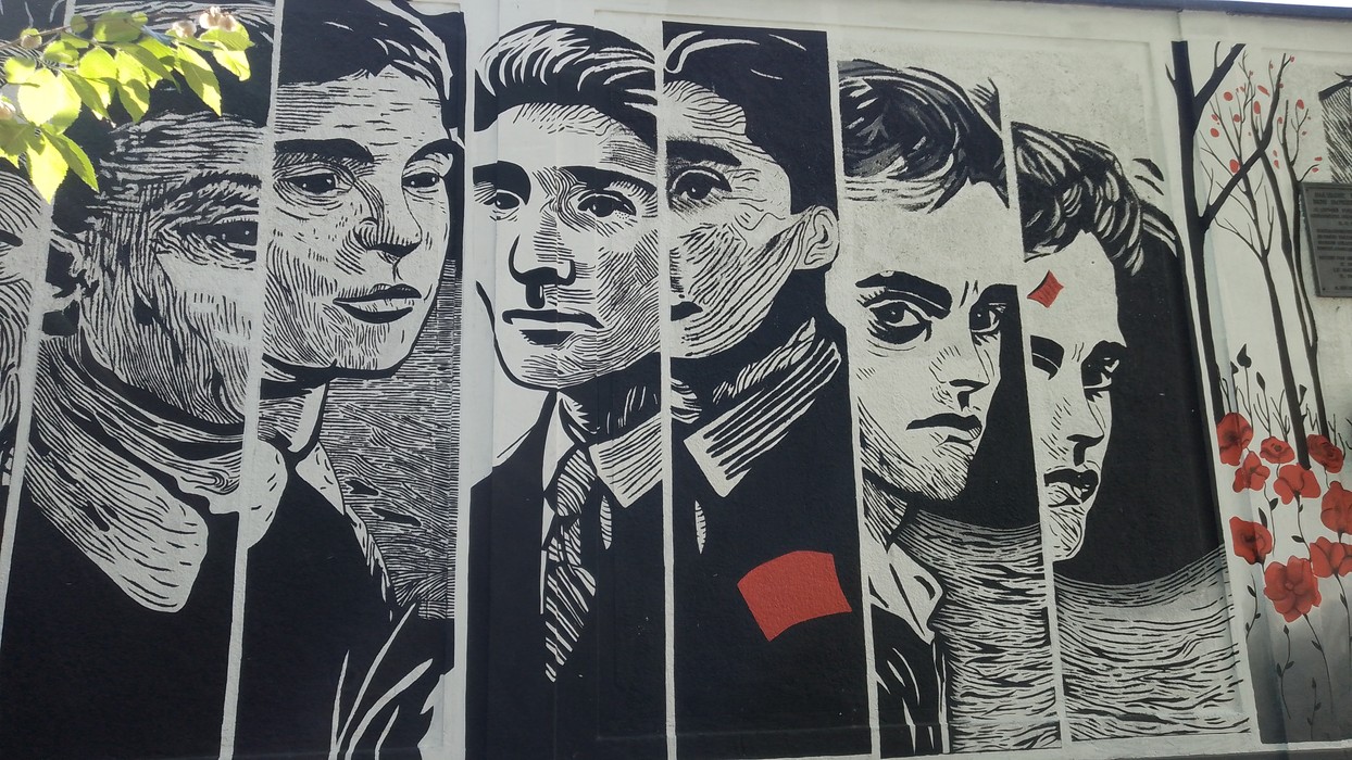 Murale che ritrae volti espressivi dei ragazzi di Via Botticelli, con dettagli in bianco e nero.