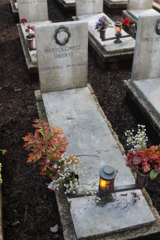 Tombe con decorazioni floreali e candele, dedicate ai caduti per la Libertà, in un contesto celebrativo.