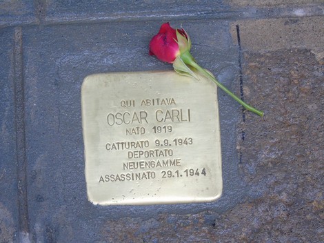 Pietra d'inciampo dedicata a Oscar Carli, con una rosa posata sopra, commemorando la sua vita e deportazione.