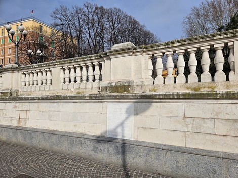 Lapide commemorativa che ricorda i fucilati della Montagnola, situata in un'area urbana con alberi sullo sfondo.
