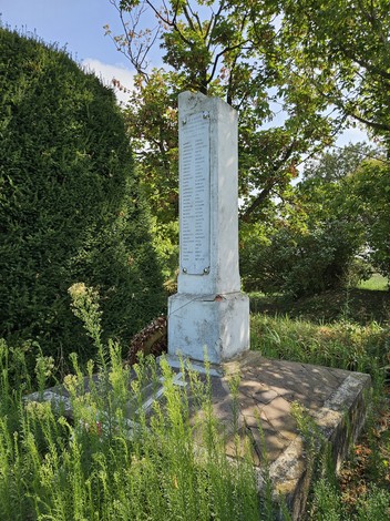 Monumento ai Martiri di Sabbiuno immerso nel verde, con una stele commemorativa visibile.