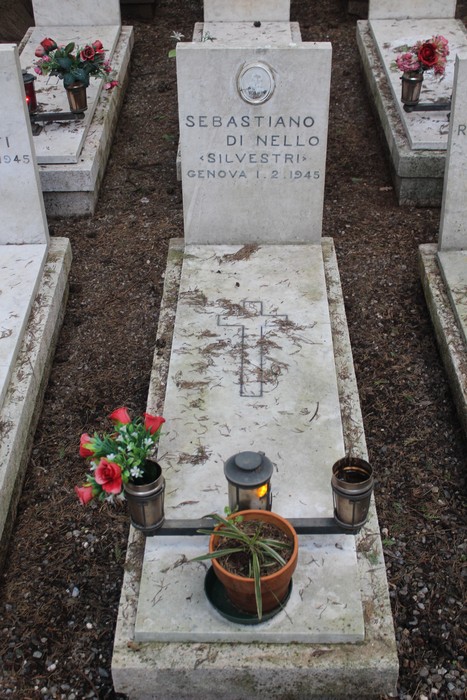 Tombe bianche adornate con fiori e luci, commemorano i caduti per la Libertà. Atmosfera di rispetto e memoria.