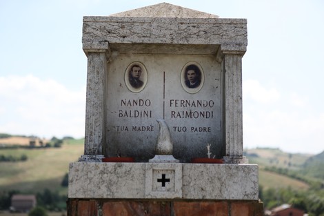 Cippo commemorativo dedicato a Nando Baldini e Fernando Raimondi, con sfondo di colline.
