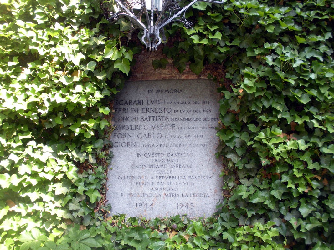 Lapide commemorativa ai torturati del Castello di Cigognola, 1944-1945, circondata da edera.