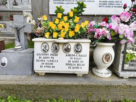 Ceramica commemorativa con fotografie e fiori, dedicata ai caduti della Creda, in un cimitero.