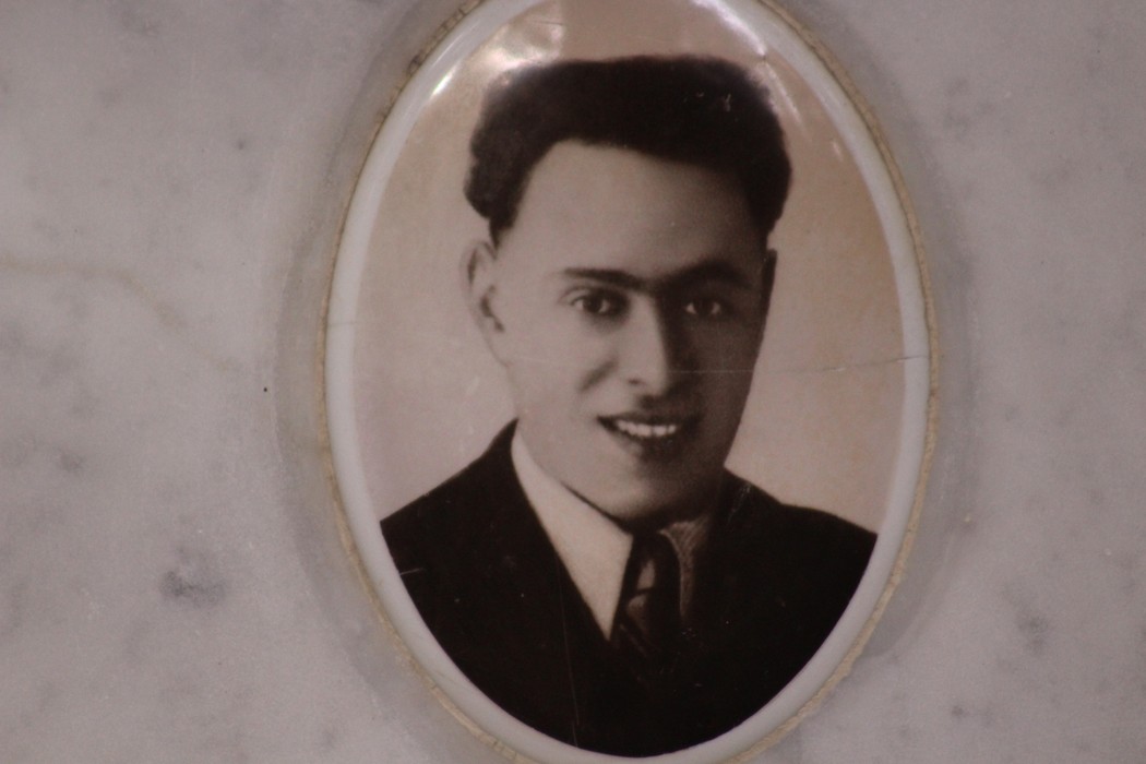 Ritratto di un giovane uomo in abito formale, conservato in un'incorniciatura ovale su marmo.