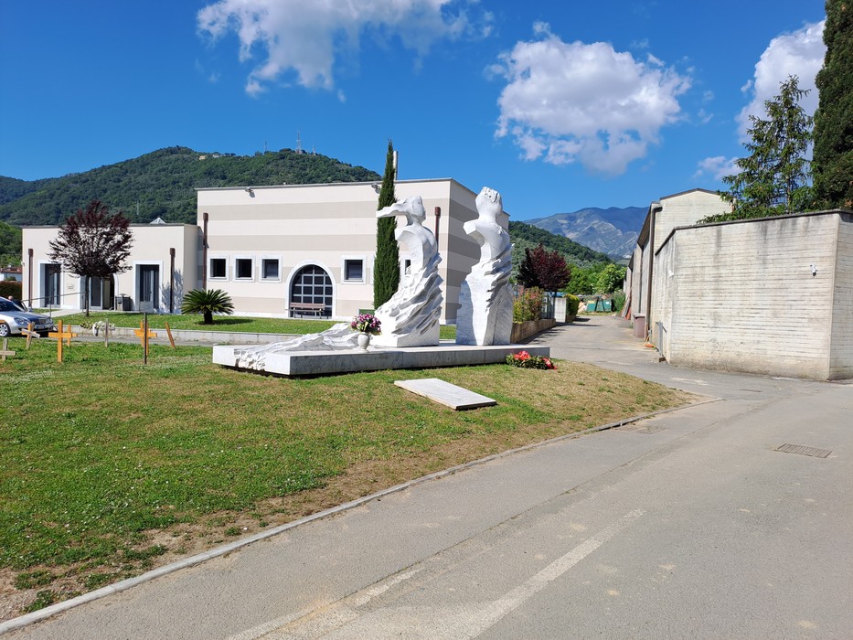 Il monumento a Brucellaria si erge in un'area verde, circondato da edifici e montagne sullo sfondo.