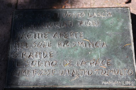 Monumento alla Resistenza antifascista con rilievi commemorativi e messaggi di pace.
