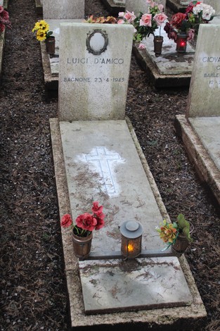 Tomba di Luigi D'Amico con fiori e lampada, commemorando i caduti per la Libertà. Atmosfera di rispetto e memoria.