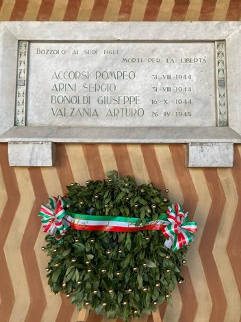 Lapide commemorativa ai caduti partigiani di Bozzolo, con corona di alloro e fasce tricolori.