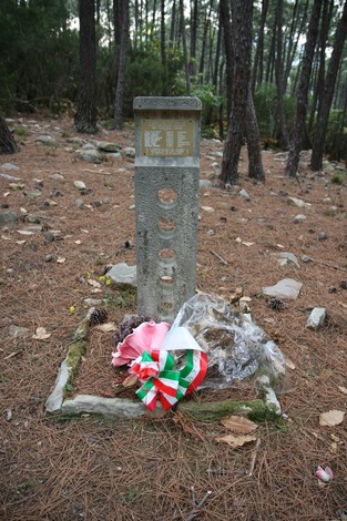 Cippo commemorativo circondato da alberi e decorazioni floreali in onore di Bulleri e altri.