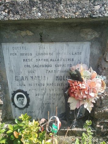 Cippo commemorativo dedicato a Gian Maria Molinari con decorazioni floreali e iscrizione in marmo.