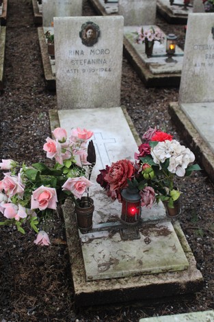 Tombe con fiori e candele, commemorano i caduti per la Libertà in un ambiente di rispetto e memoria.