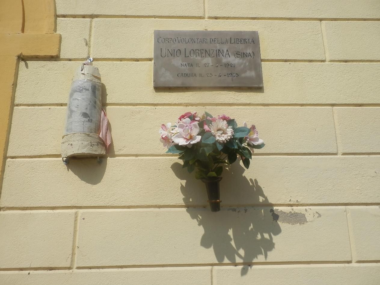 Lapide commemorativa dedicata a Unio Lorenzi, con decorazioni floreali e simbolo della libertà.