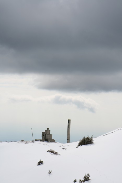 Monumento alla XI Zona "Pippo" immerso nella neve, sotto un cielo nuvoloso e suggestivo.