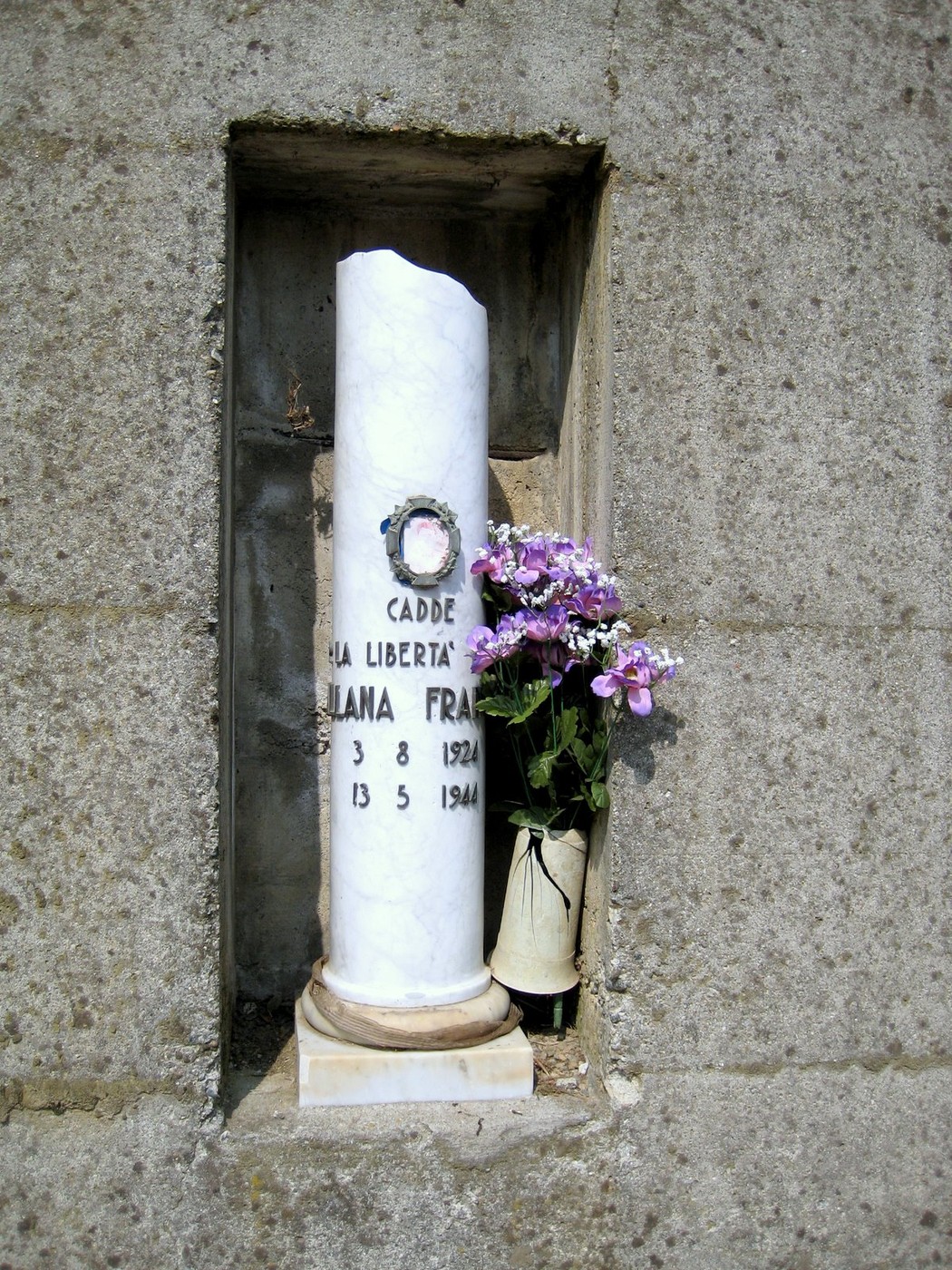Cippo commemorativo a Mallana in memoria dei caduti per la libertà, decorato con fiori.