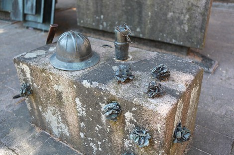 Monumento alla Resistenza antifascista con elementi in bronzo e un casco, simboli di memoria e lotta.