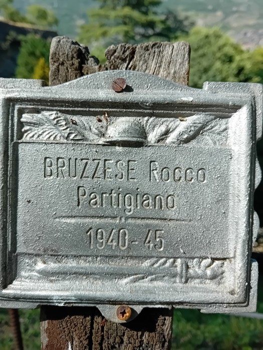 Targa commemorativa di Rocco Bruzzese, partigiano dal 1940 al 1945, affissa su un palo di legno nel Parco della Rimembranza.