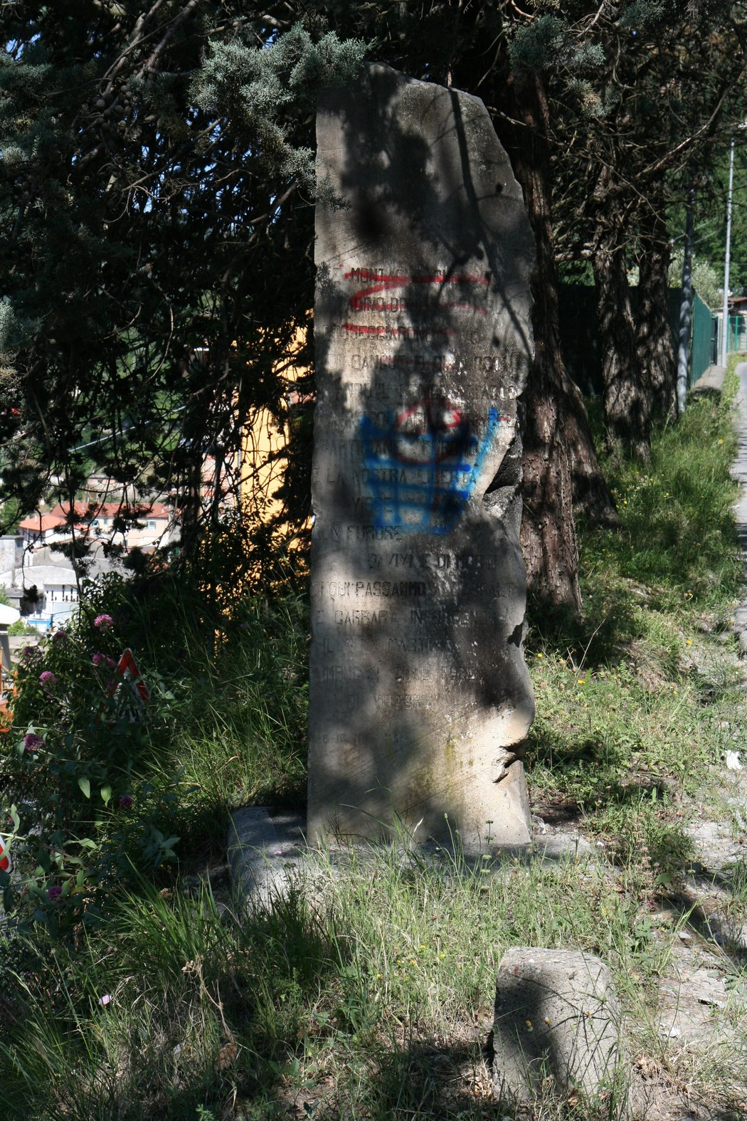 Cippo commemorativo della Liberazione, immerso nella vegetazione, simbolo di storicità e memoria.