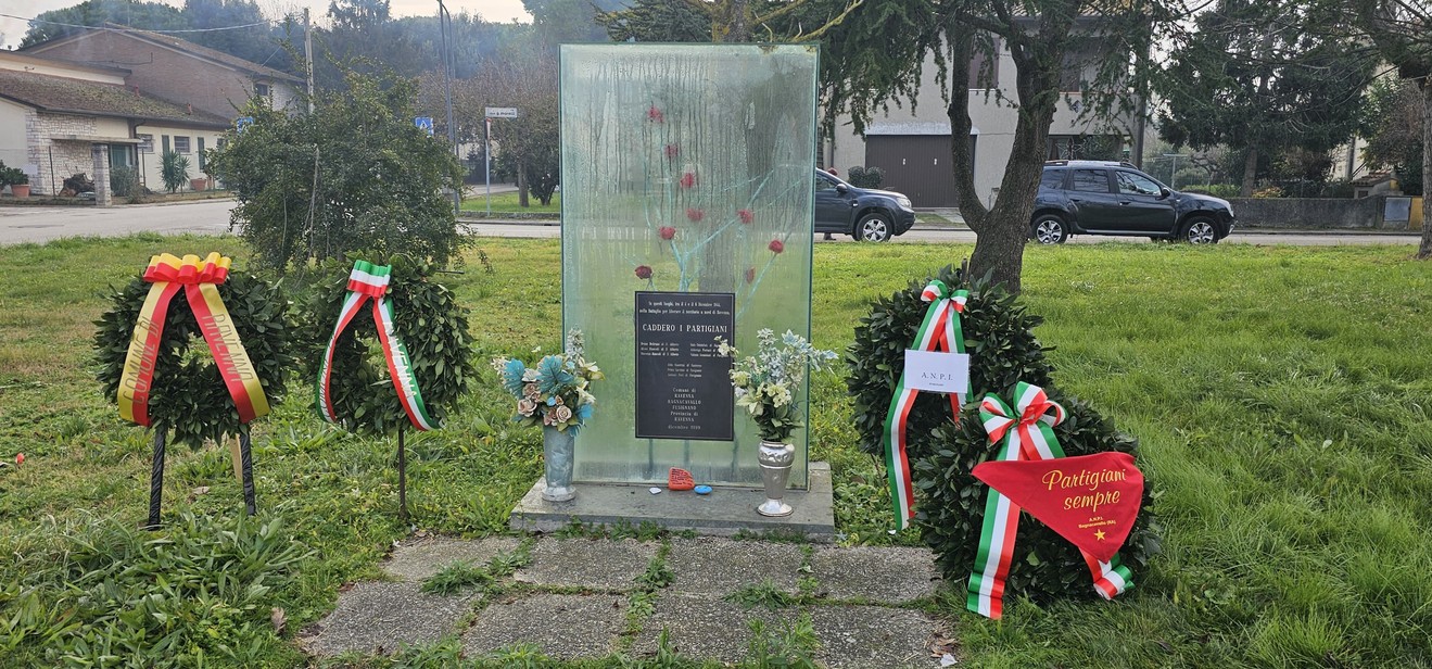 Monumento commemorativo con corone di fiori e decorazioni, in onore di Beltrami e altri.