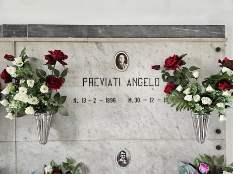 Monumento commemorativo con fiori artificiali e fotografie, dedicato ai caduti, rappresenta un tributo di memoria.