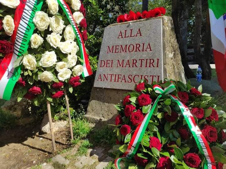 Cippo commemorativo con fiori rossi e bianchi, dedicato ai Martiri Antifascisti.